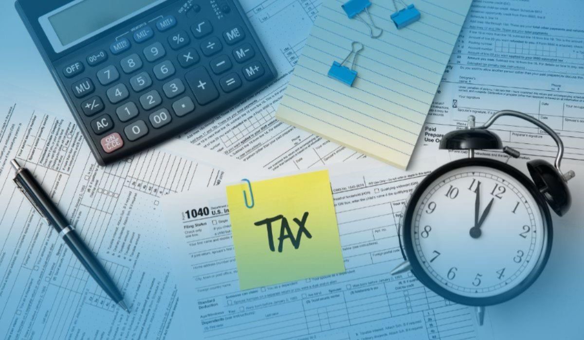 Tax documents and calculator on a desk with a TAX sticky note